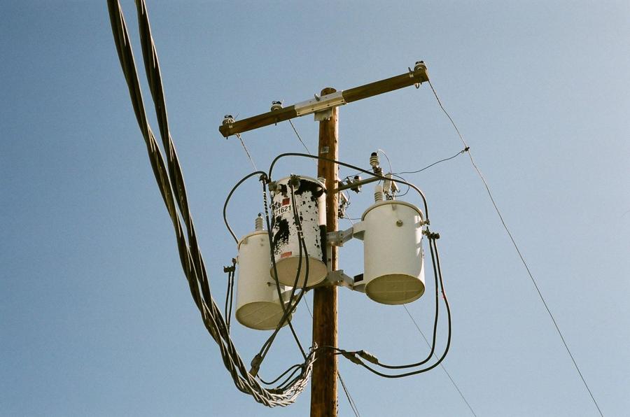 Closeup of an electrical pole with wiring and against a blue sky