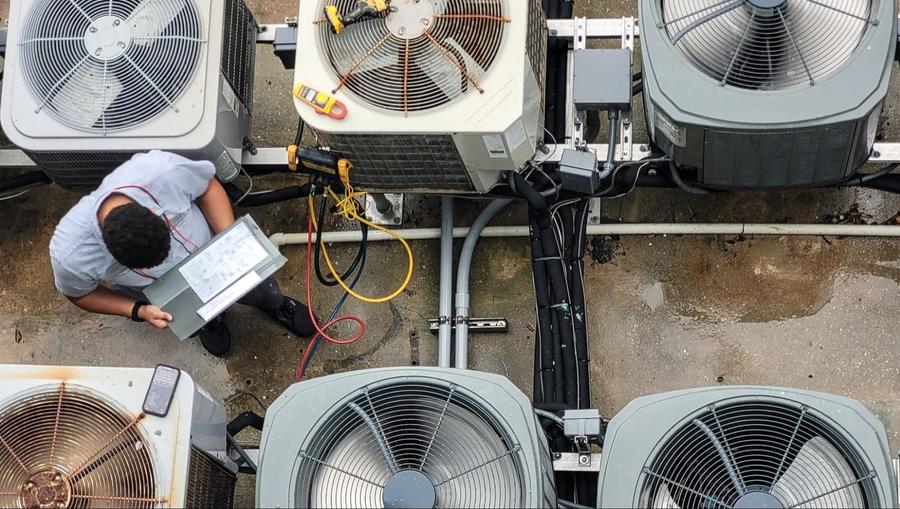 Technician inspecting multiple heat pumps