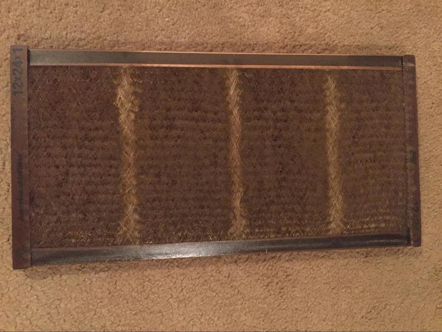 An air filter clogged with black dust/soot