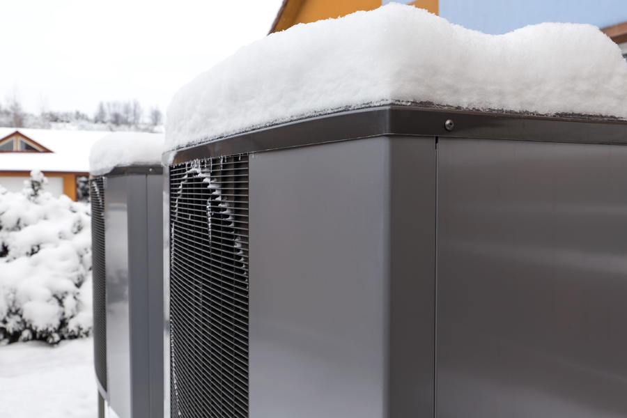Two ductless heat pumps covered in snow sitting side by side.